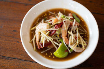 Fresh shrimp salad with papaya in white plate on wooden table