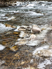 A turbulent mountain river in winter, crystal clear water rushing between the stones