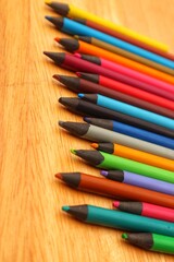 Colorful pencils lined up isolated on a wooden background, close up view.