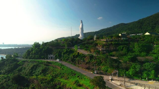 Aerial perspective revealing white lady buddha statue towering over verdant landscape near ho quoc pagoda, symbolizing spiritual tranquility on phu quoc island, vietnam