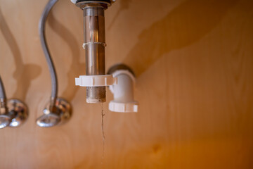 selective focus on a bathroom sink drain disconnected with a hair clog hanging down