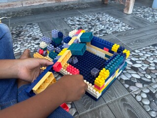 A close-up of child hands assembling colorful building blocks, creating a toy structure. Perfect for concepts of creativity, childhood development, education, and playtime activities for kids