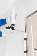 in the hands of a worker, a cylinder under pressure for applying mounting foam, when installing an...