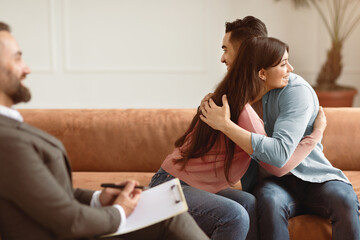Making Peace. Happy young married couple hugging after successful therapy session with man...