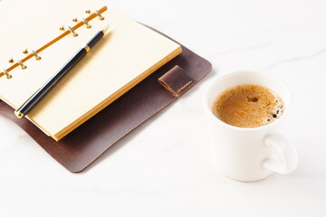 ミルクをたっぷり入れたコーヒー、カフェ・ラッテを飲みながら、システム手帳でデスクワーク中のイメージ
