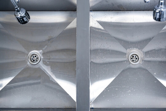 Cleaning stainless steel sinks in a commercial kitchen after meal preparation