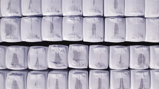 Drone top down pan of large peat BB bags neatly arranged in rows, showcasing industrial storage layout