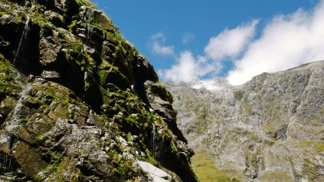 lush cliffside drippy waterfall with mountains in background