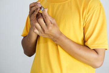A person using a nail clipper while wearing a yellow t-shirt on a light background