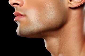Obraz premium A close-up profile of a man's face showcasing his defined jawline and smooth skin against a black background.