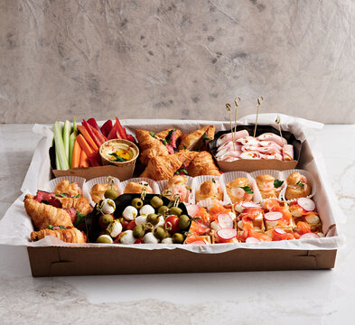 A large catering platter displays an array of savory pastries, fresh vegetables, and dips, ideal for social gatherings. Colorful arrangements include croissants, olives, and carrot sticks