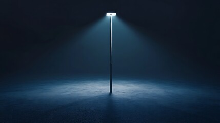 A modern, minimalistic streetlight pole lit up during the night, casting long shadows over an empty road.