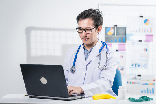 A male nutritionist working at a hospital desk, holding an apple and mixed fruit, offering care, health advice, weight loss guidance, and eating tips online for patients seeking nutrition support