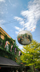disco ball on blue sky background with white clouds and colorful flags are hung in air, Georgia