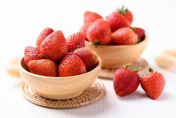 Strawberry fruit in wooden bowl on white background