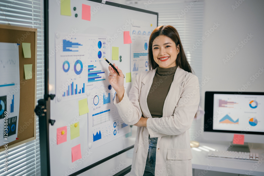 Poster smiling businesswoman explaining charts and graphs on whiteboard during a presentation in office