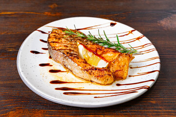 Grilled salmon steak with citrus glaze and herbs on a rustic plate Savory vegetable pie served with fresh garnishes on a white plate