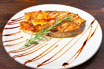 Grilled salmon steak garnished with herbs and sauce on a plate Savory vegetable pie served with fresh garnishes on a white plate