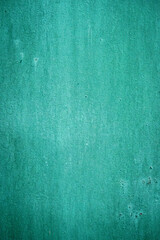 A simple yet striking photograph of a green textured wall, showcasing subtle gradients and imperfections in the surface. The texture adds depth and character to the otherwise minimalistic composition.
