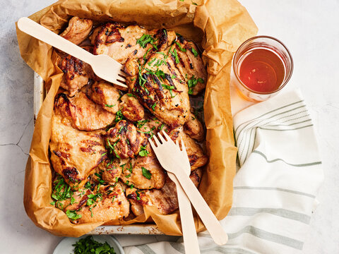 Succulent grilled chicken pieces rest in a serving tray, garnished with fresh herbs. A glass of refreshing drink sits nearby, perfect for sharing