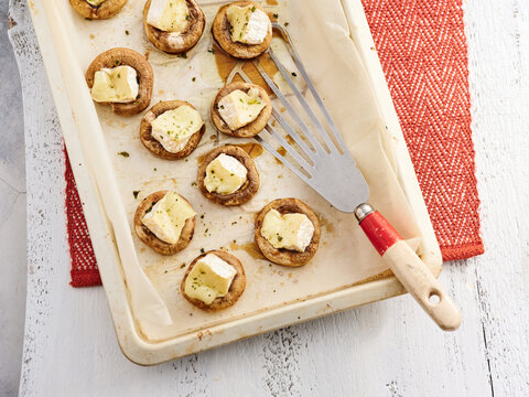 A tray holds freshly baked mushroom appetizers topped with melted cheese, showcasing delicious bite-sized treats perfect for entertaining guests
