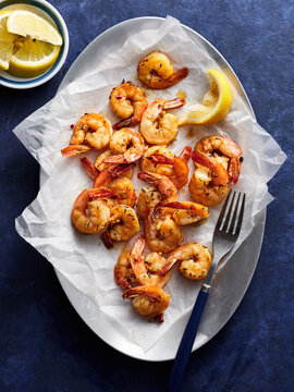 Succulent grilled shrimp are beautifully arranged on a white platter, garnished with fresh lemon wedges. Perfect for a seafood feast or casual gathering