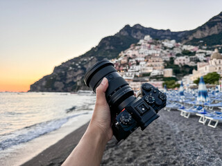 Camera in hand with view over Positano town and beach in Amalfi coast in Italy.