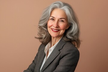 Cheerful old woman in office attire, isolated on soft brown background.