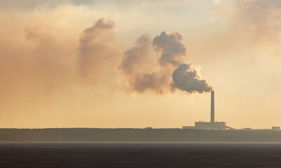 A large smoke stack is visible in the distance
