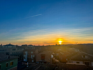 Fototapeta premium As the sun slowly sets down over the sprawling city, the silhouettes of buildings rise prominently in the foreground against the vibrant sky