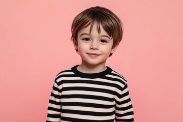 Cute boy in a striped sweater, isolated on pink.