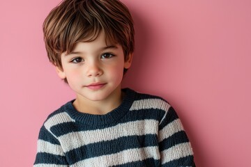 Cute boy in a striped sweater, isolated on pink.