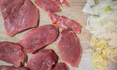 Chef preparing pork tenderloin with chopped onions and garlic on cutting board