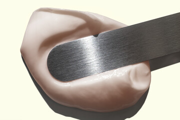 Cosmetic beauty skin care product with steel spatula on grey background