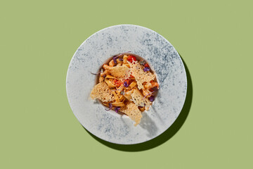 A vibrant and colorful plate of pasta topped with cherry tomatoes, fresh herbs, and crispy parmesan