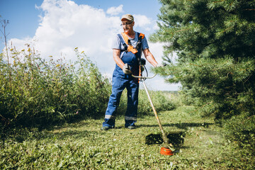 Senior man mowing grass with a hand-held trimmer 