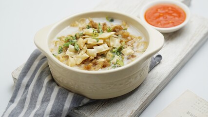 Bubur Ayam, Indonesian rice porridge served with shredded chicken and wonton crackers isolated white background