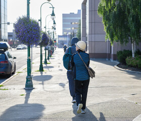 Tourists walking on the  pedestrian sidewalk at downtown Anchorage. Purple flower baskets hanging...