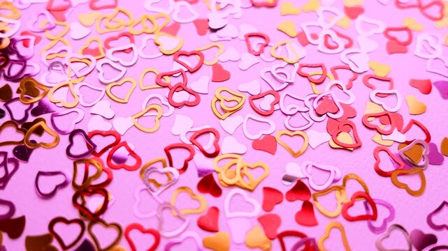 Hearts confetti on pink background for Valentines Day. Love concept. Glitter confetty heatrs golden, red and pink footage