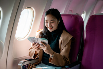 Young businesswoman counting money while traveling on an airplane