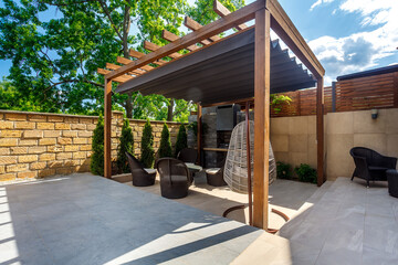 Backyard outdoor bbq zone with pergola, fireplace and hanging chair. Summer party place