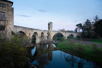 Medieval stone bridge leading to picturesque village in catalonia
