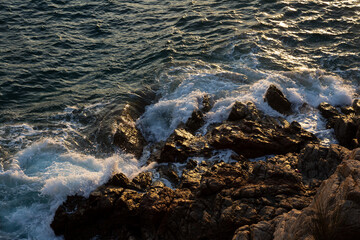 Ocean waves crashing on rocks in a sunny day