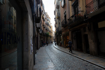 Tourists walking down narrow cobblestone street in girona, spain