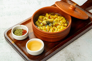 Traditional stew served in a clay pot with condiments on a wooden tray