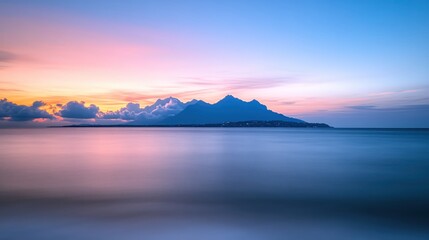 Serene seascape with mountain silhouette at dusk in soft pastel colors and smooth water surface