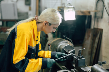 female worker using vernier caliper measuring metal part in lathe machine in heavy metal workshop