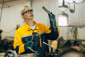 female worker using vernier caliper measuring metal part in lathe machine in heavy metal workshop