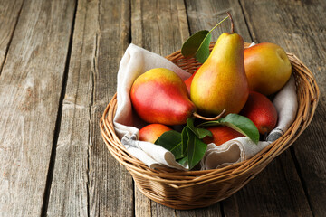 Ripe juicy pears in wicker basket on wooden table