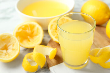Fototapeta premium Glass of fresh lemon juice and squeezed fruits on table, closeup